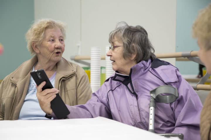Valerie Phillips (right) showing her friend something on her phone at the Big Venture Centre official opening, a new community owned community hub secured by asset transfer.