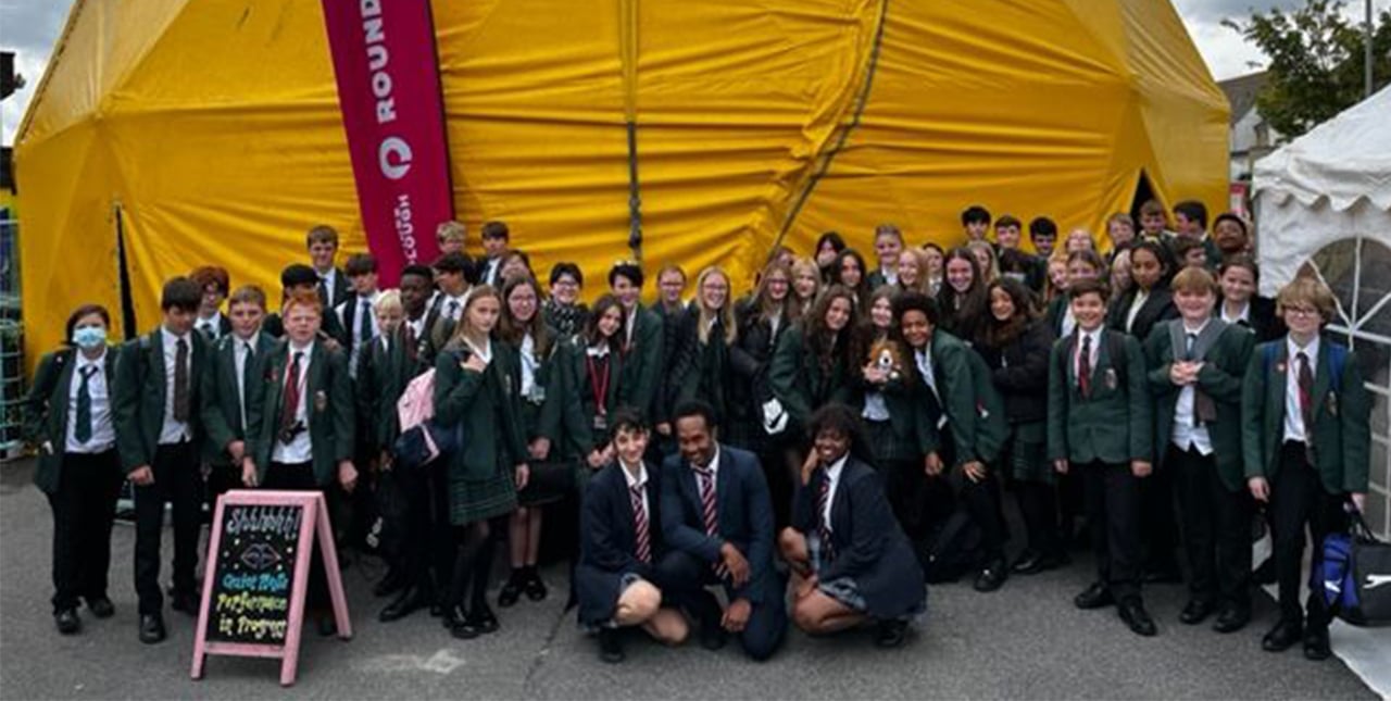 A class of school children standing outside the yellow tent that will hold the Roundabout festival