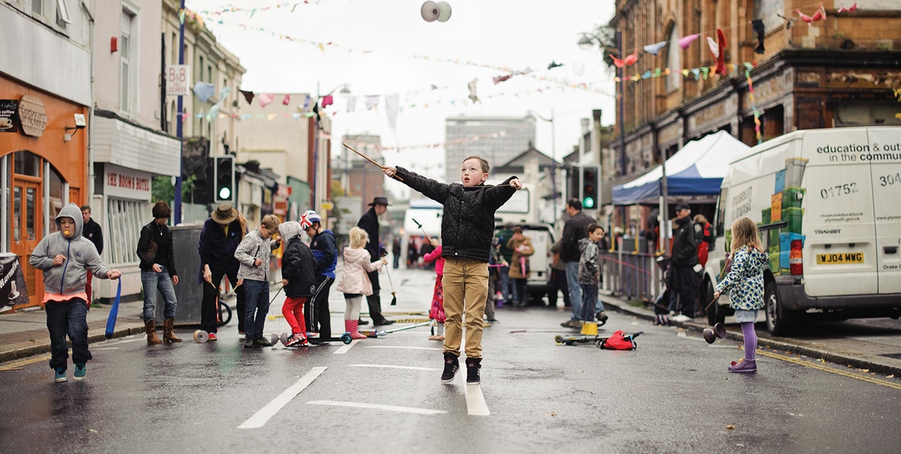 A street with bunting, and children learning circus skills