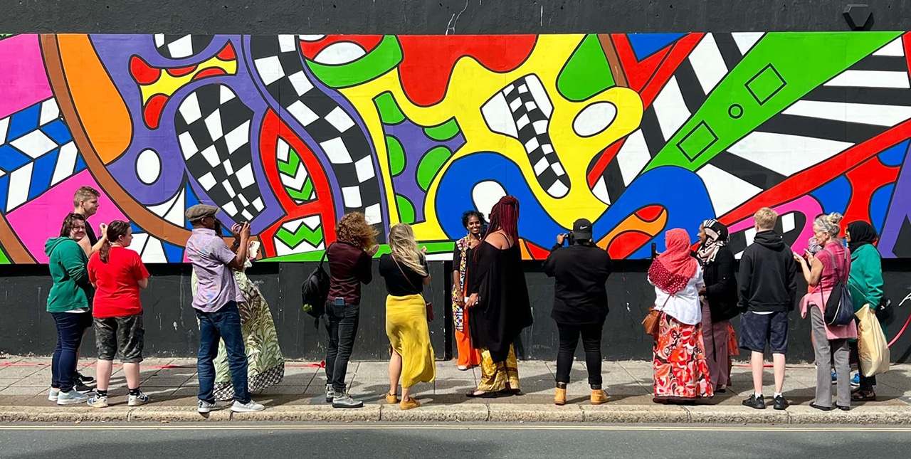 A group looking at a wide, colourful mural