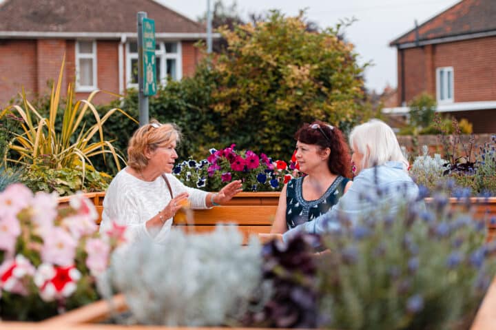 Local residents chatting on a bench surrounded by flowers