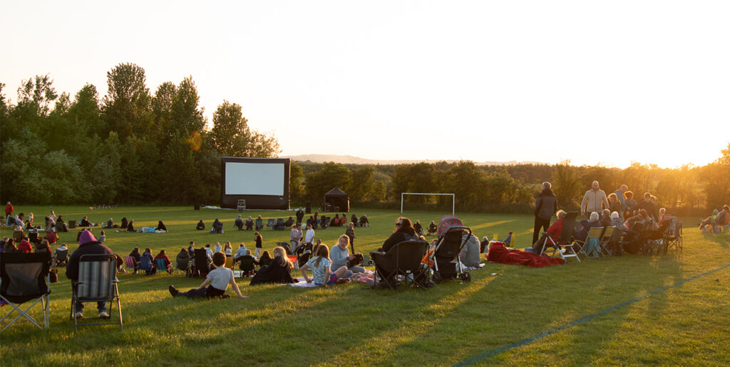 Residents sit on a field for cinema night