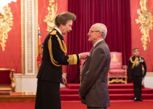 Anne, princess Royal, pins an award on David Warner, MBE