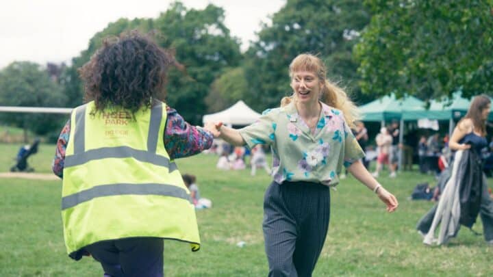 A woman in a high viz jacket hands a baton to