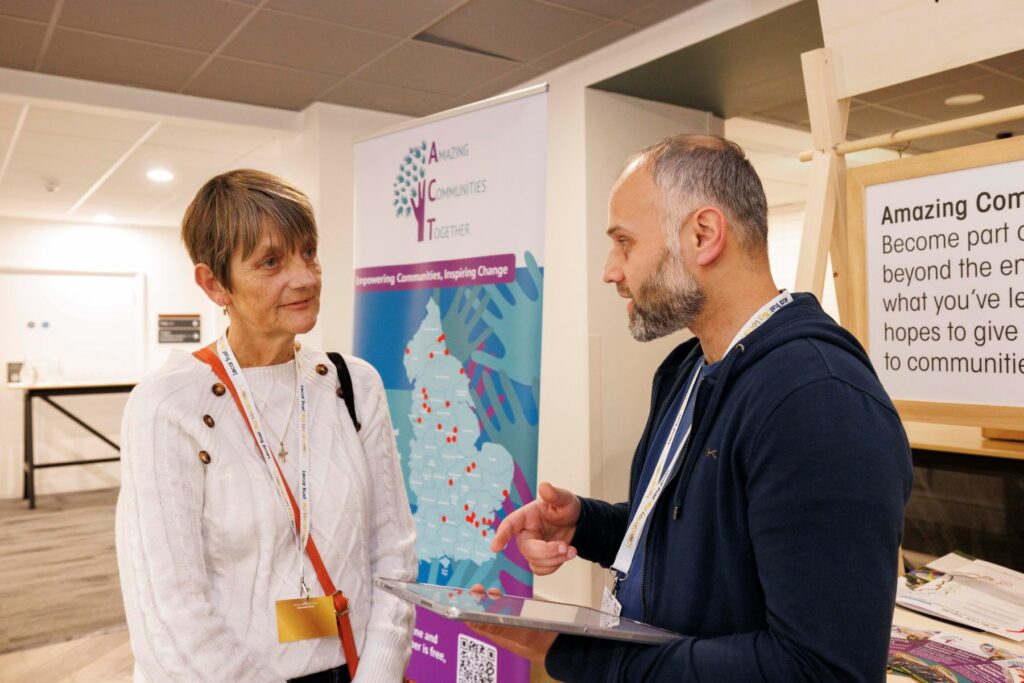 A man talks to a woman by a booth with an ipad