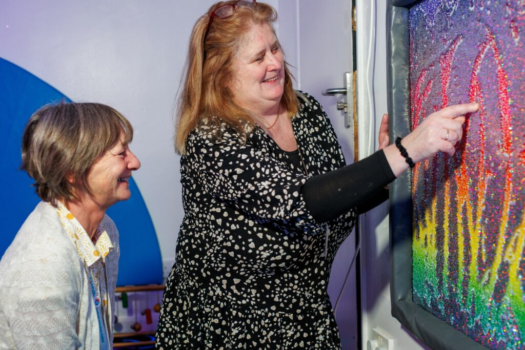 Jan Papworth (L) and Lisa Henderson (R) interact with colourful sensory board