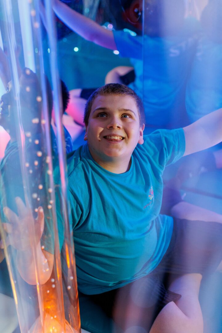 Boy wearing blue t-shirt looks up and smiles in sensory softplay centre