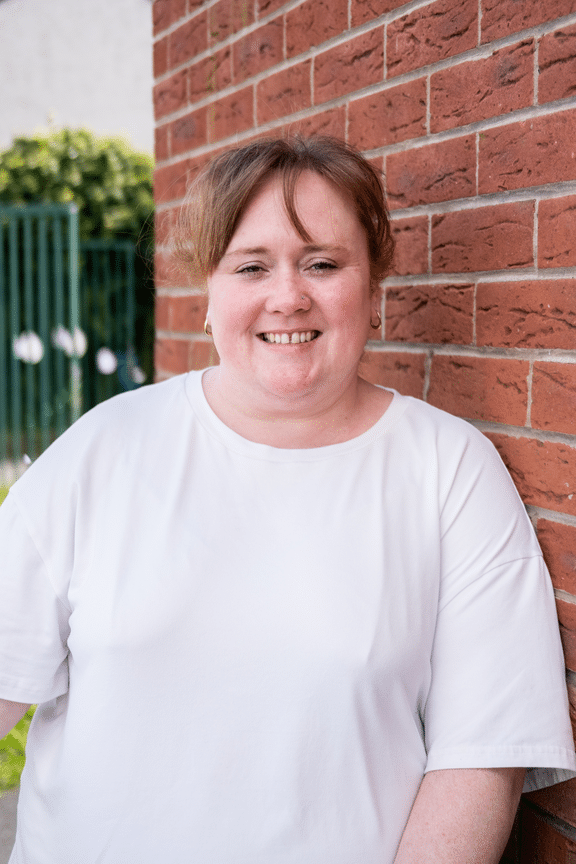 Vicky Williamson wearing white tshirt and standing against brick wall