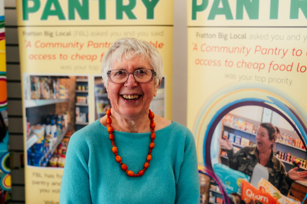 Worker Liz wearing a blue top and orange beaded necklace