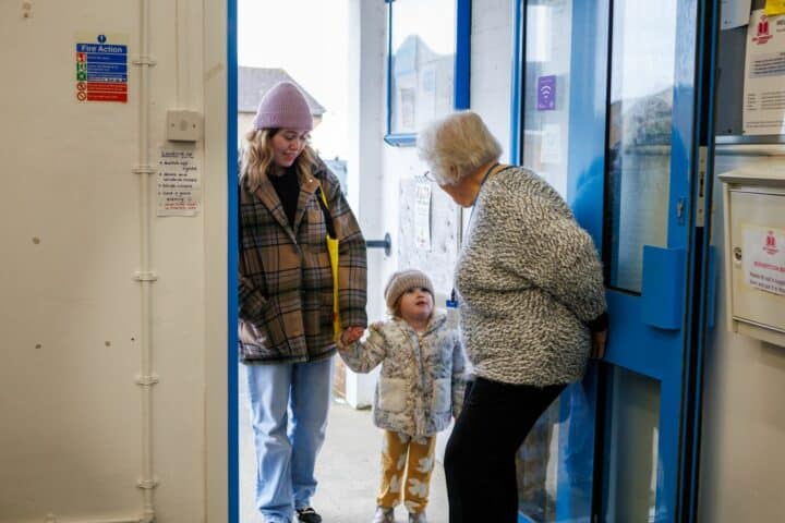 A woman lets a girl and her mother into the library