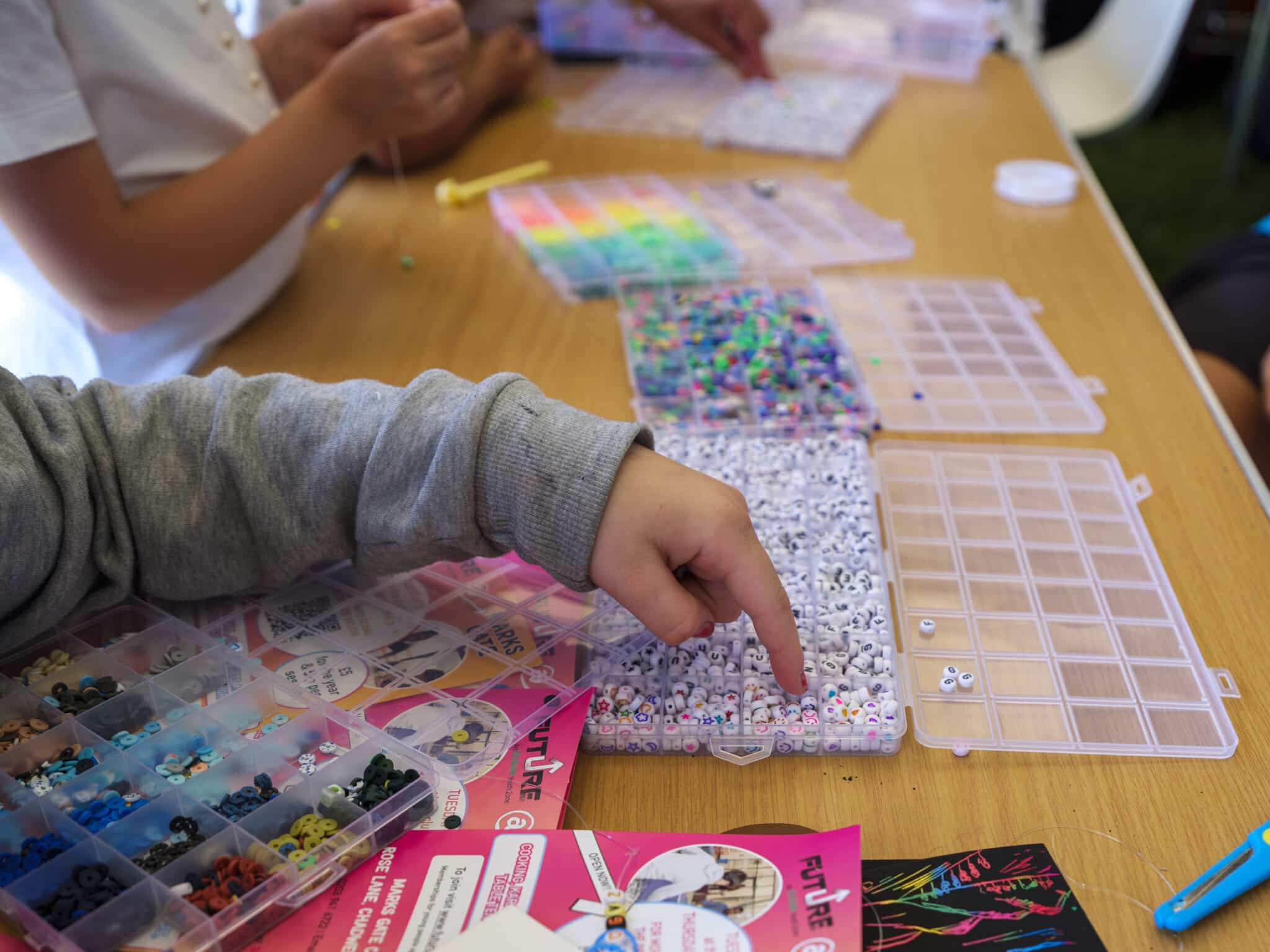 Children's hands shown in Messy Play session with colourful beads