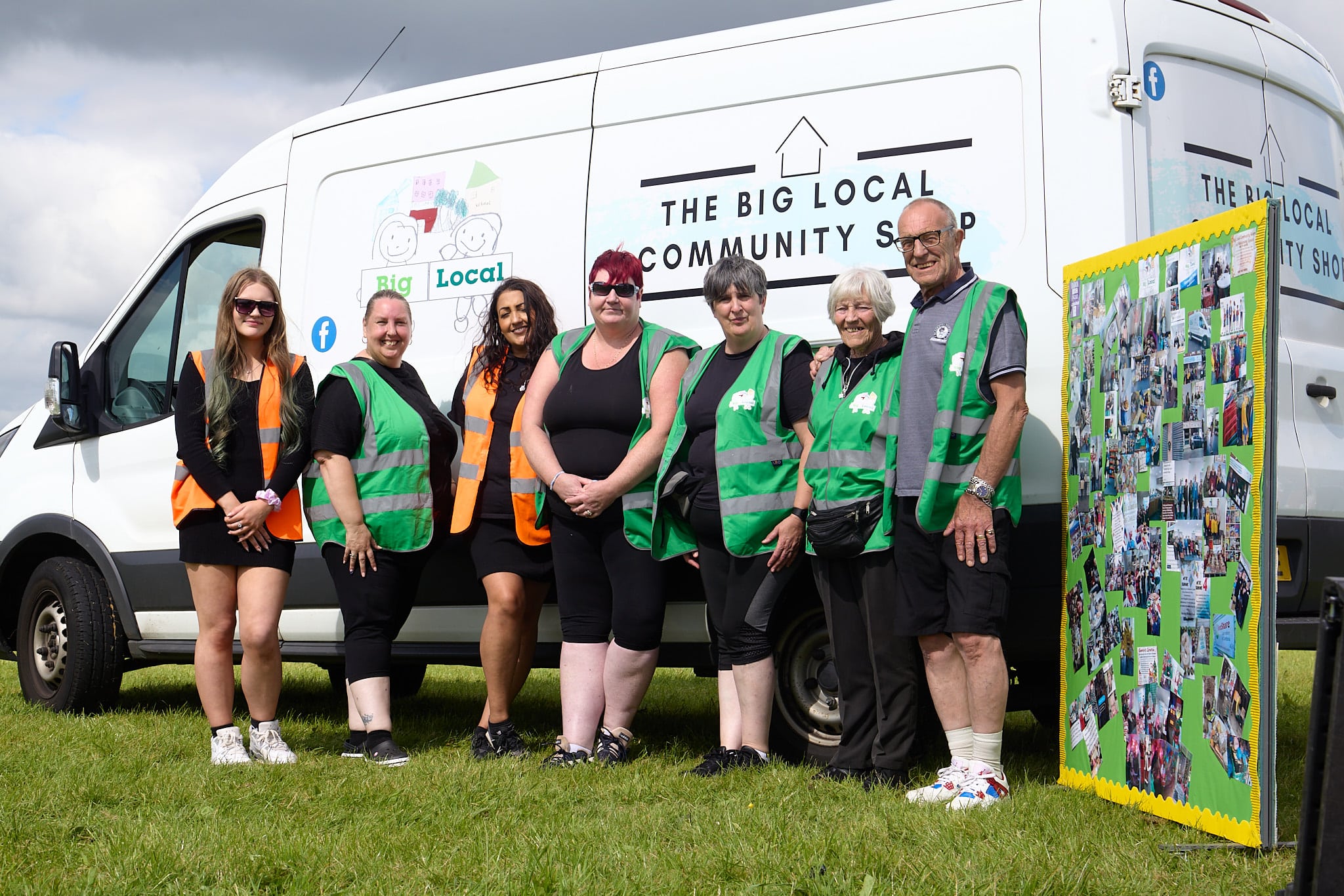 Seven people wearing high vis jackets stand in front of a white community shop van