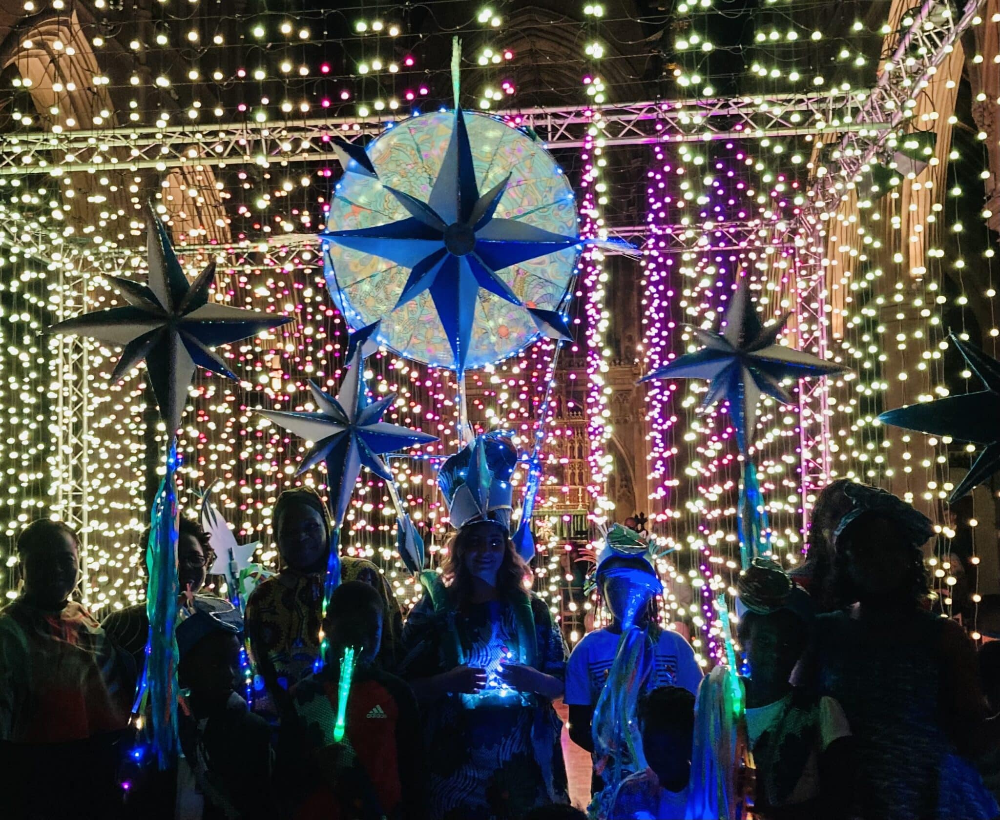 Colourful light display in front of a church at night featuring illuminated stars