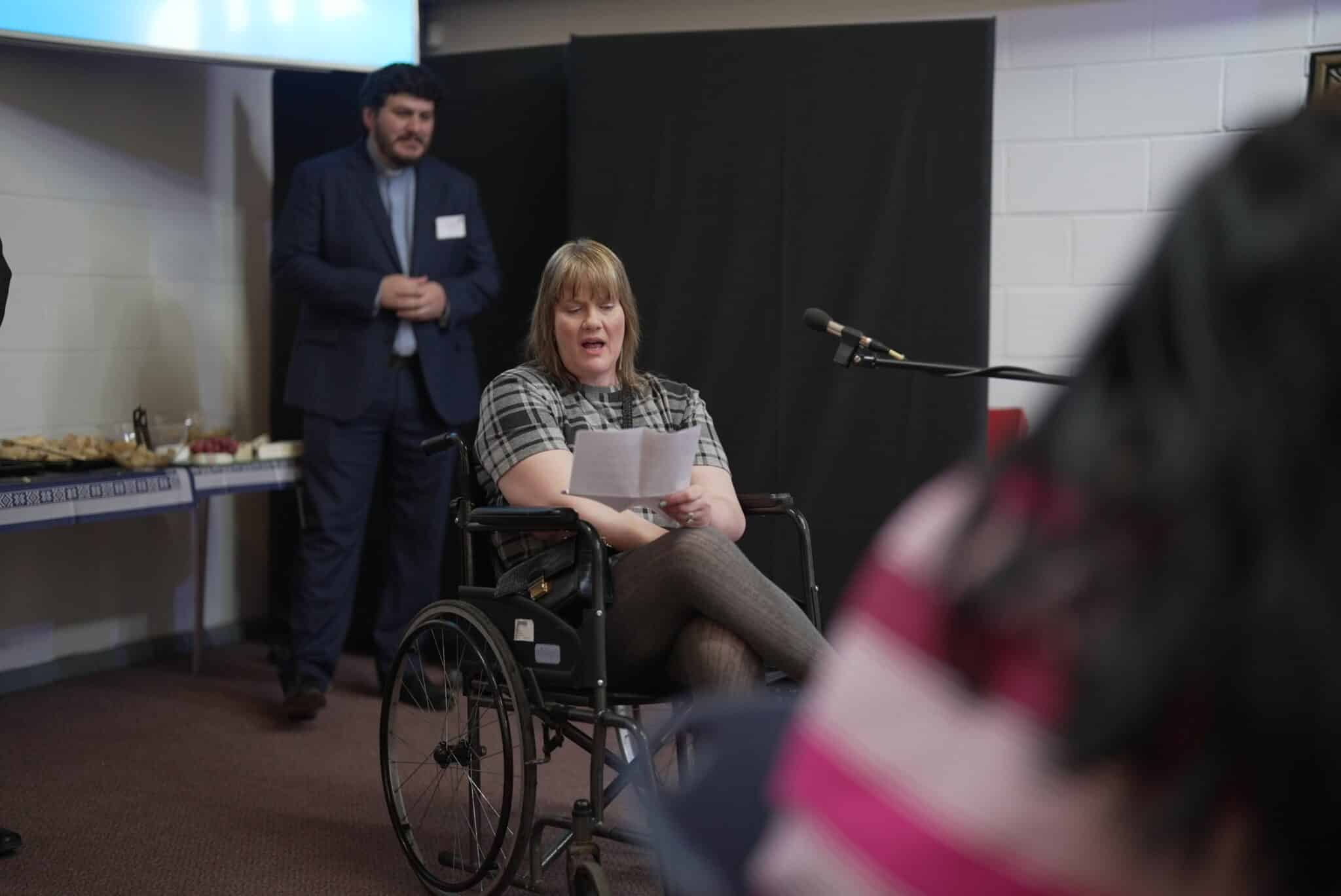 Nikki sitting in a wheelchair speaking into a microphone