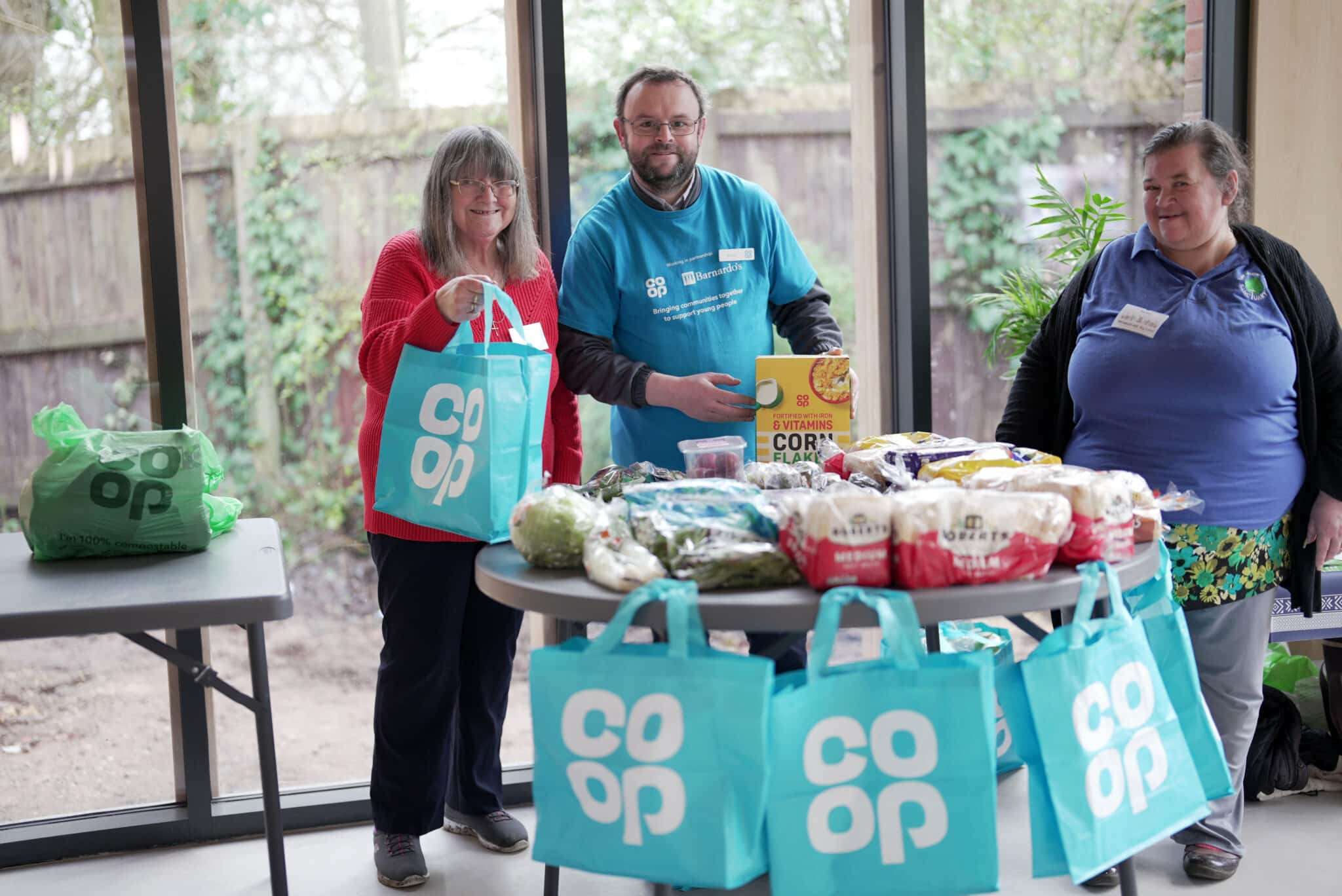 Three volunteers pack up food into Coop bags