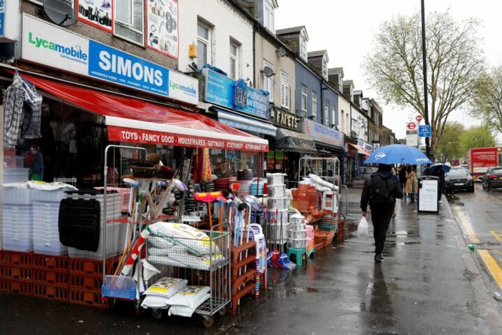 A rainy highstreet with shops down the left hand side