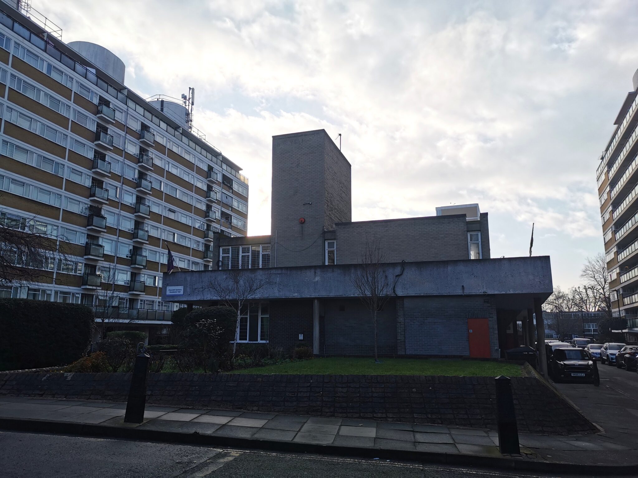 A multi-story housing estate building adjacent to a road.